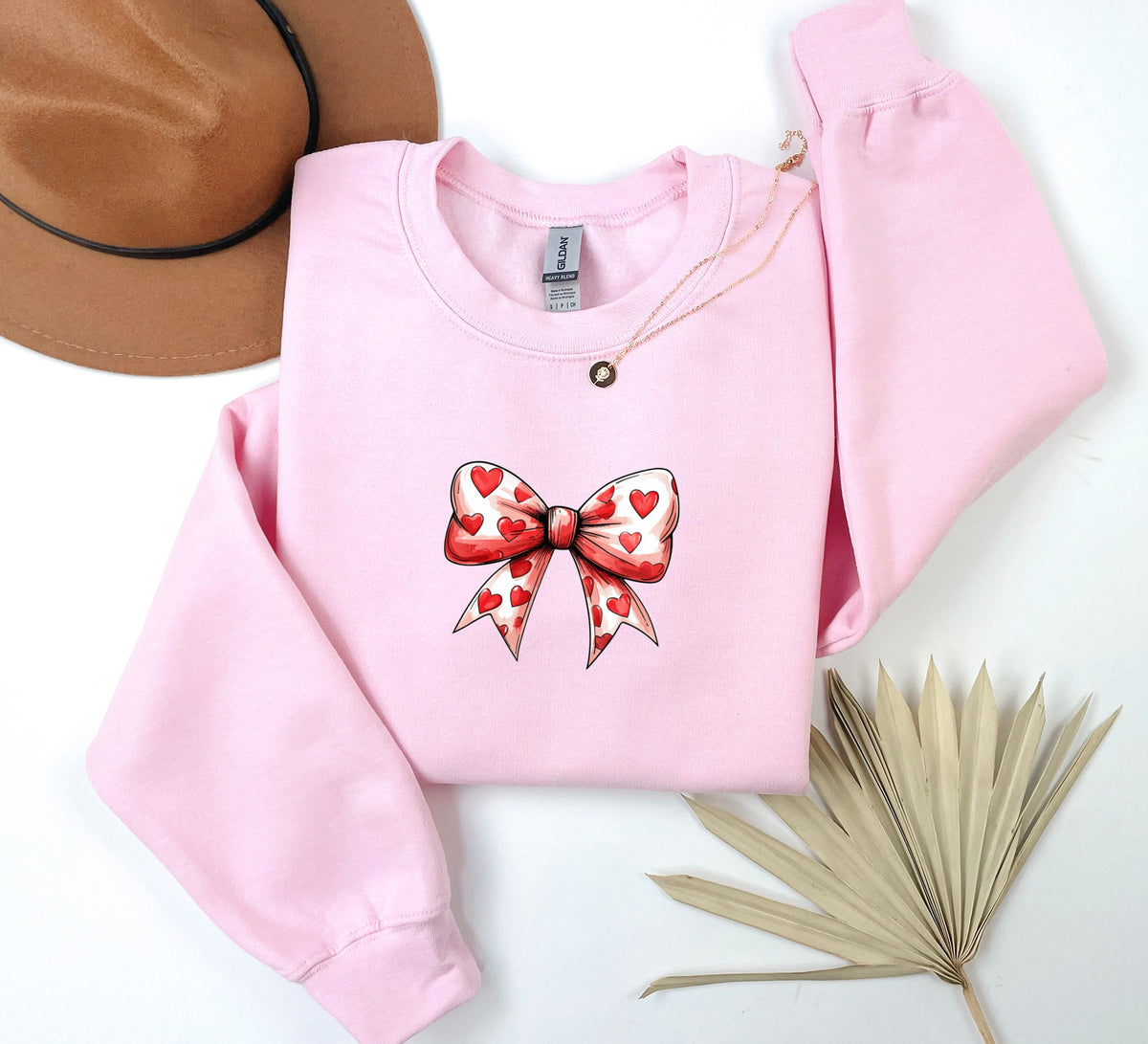 a pink sweater with a bow and hearts on it