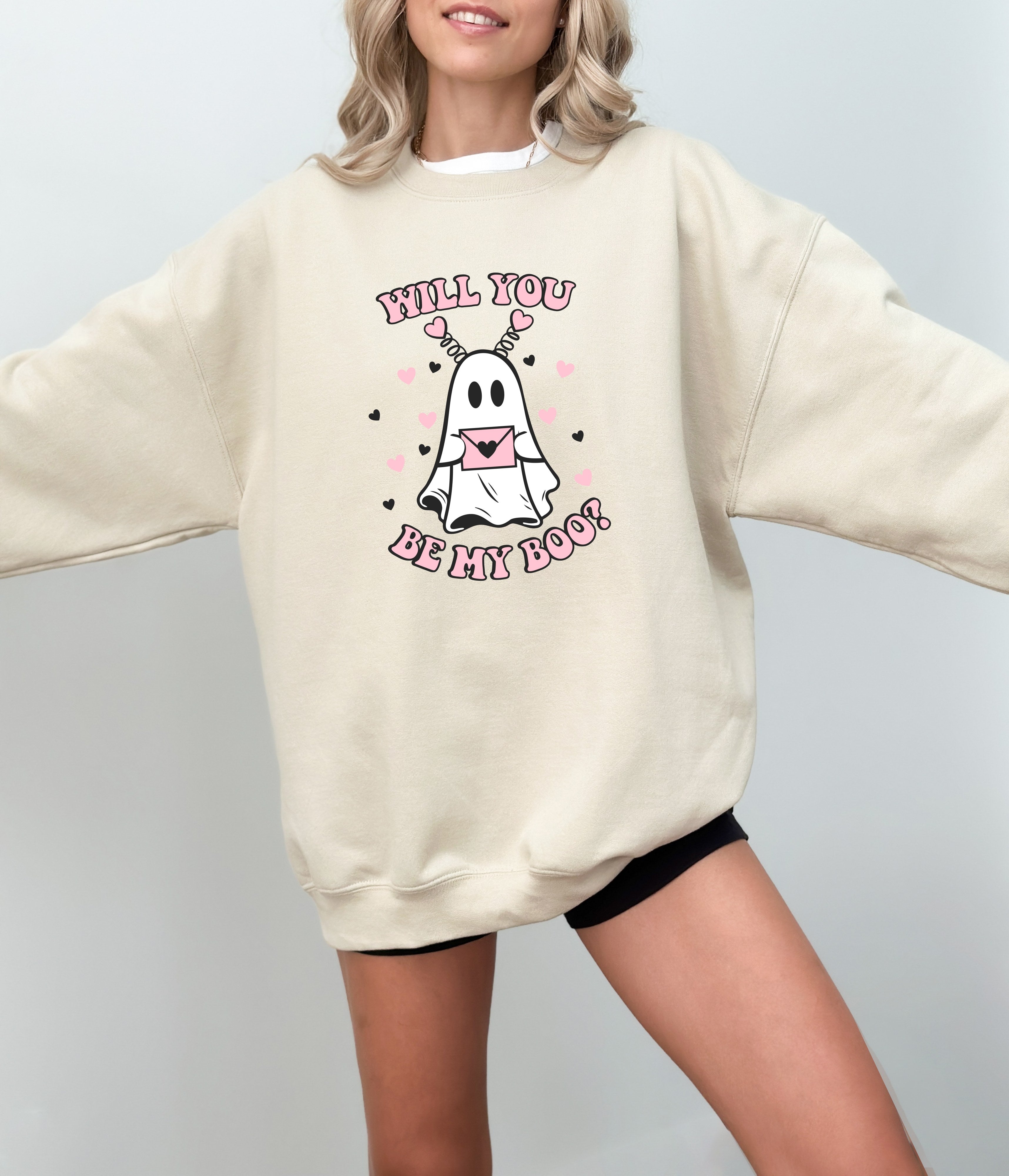 a woman wearing a sweatshirt that says, will you be my boo?