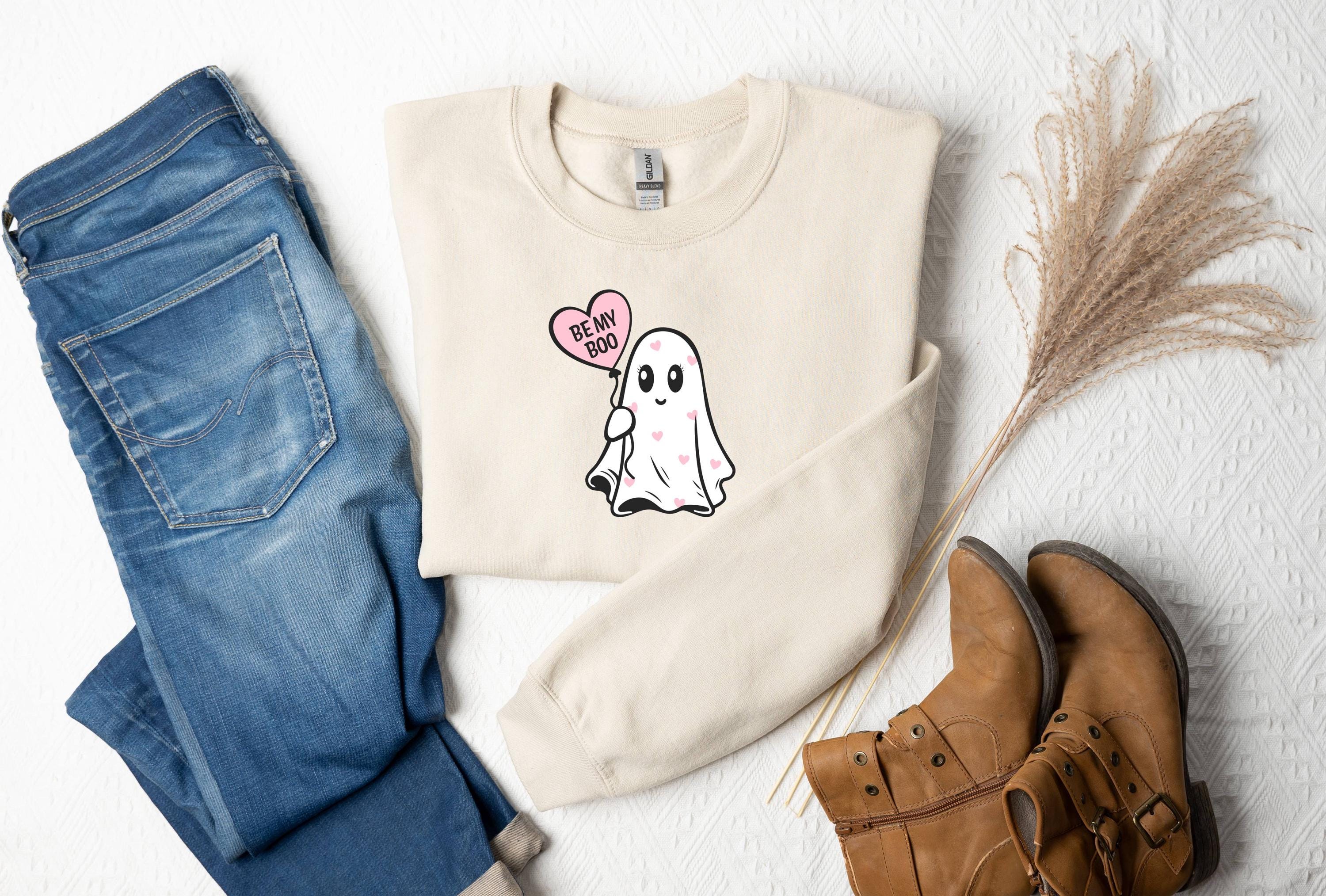 a sweater with a ghost on it next to a pair of jeans