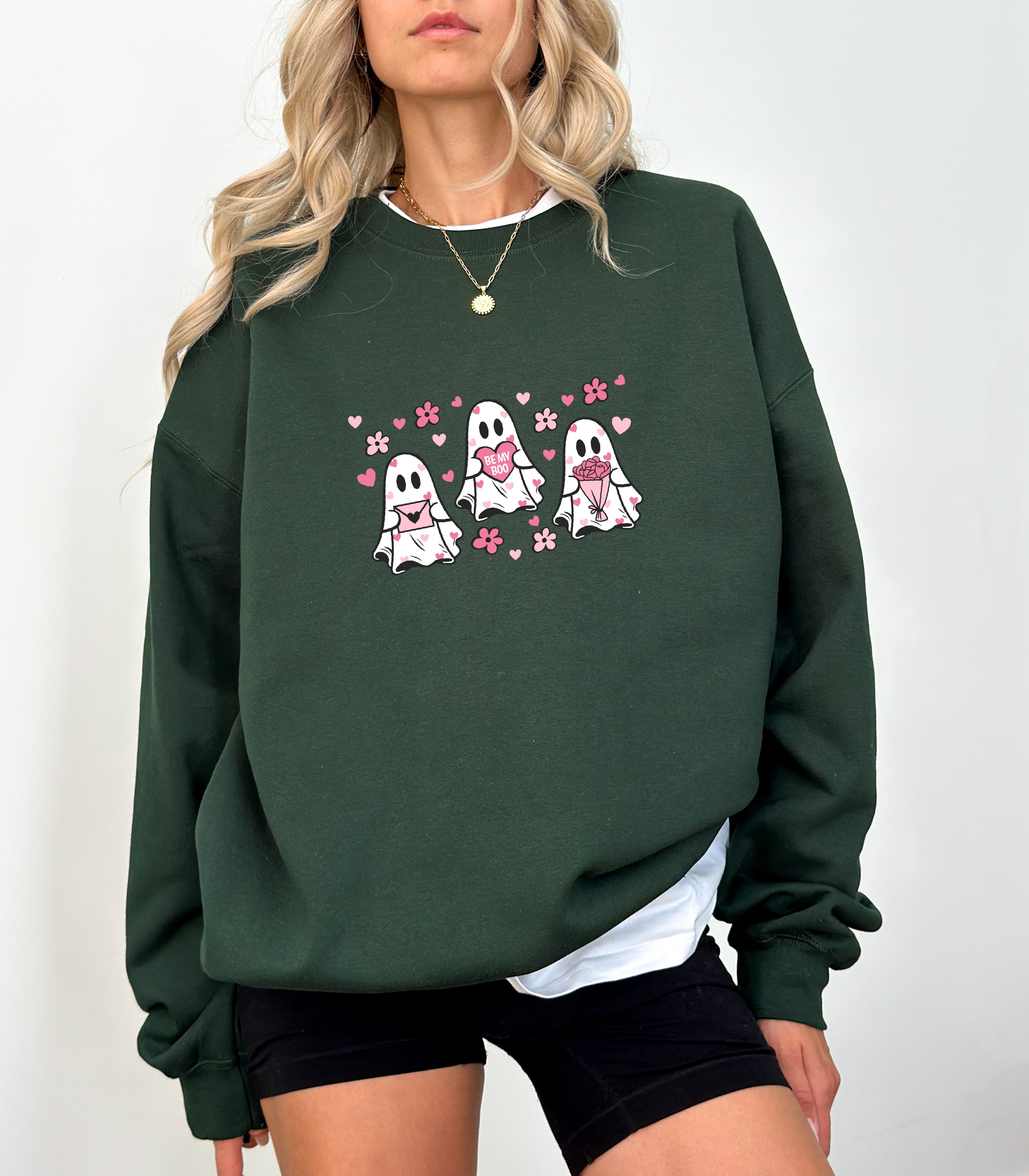 a woman wearing a green sweatshirt with two ghost on it