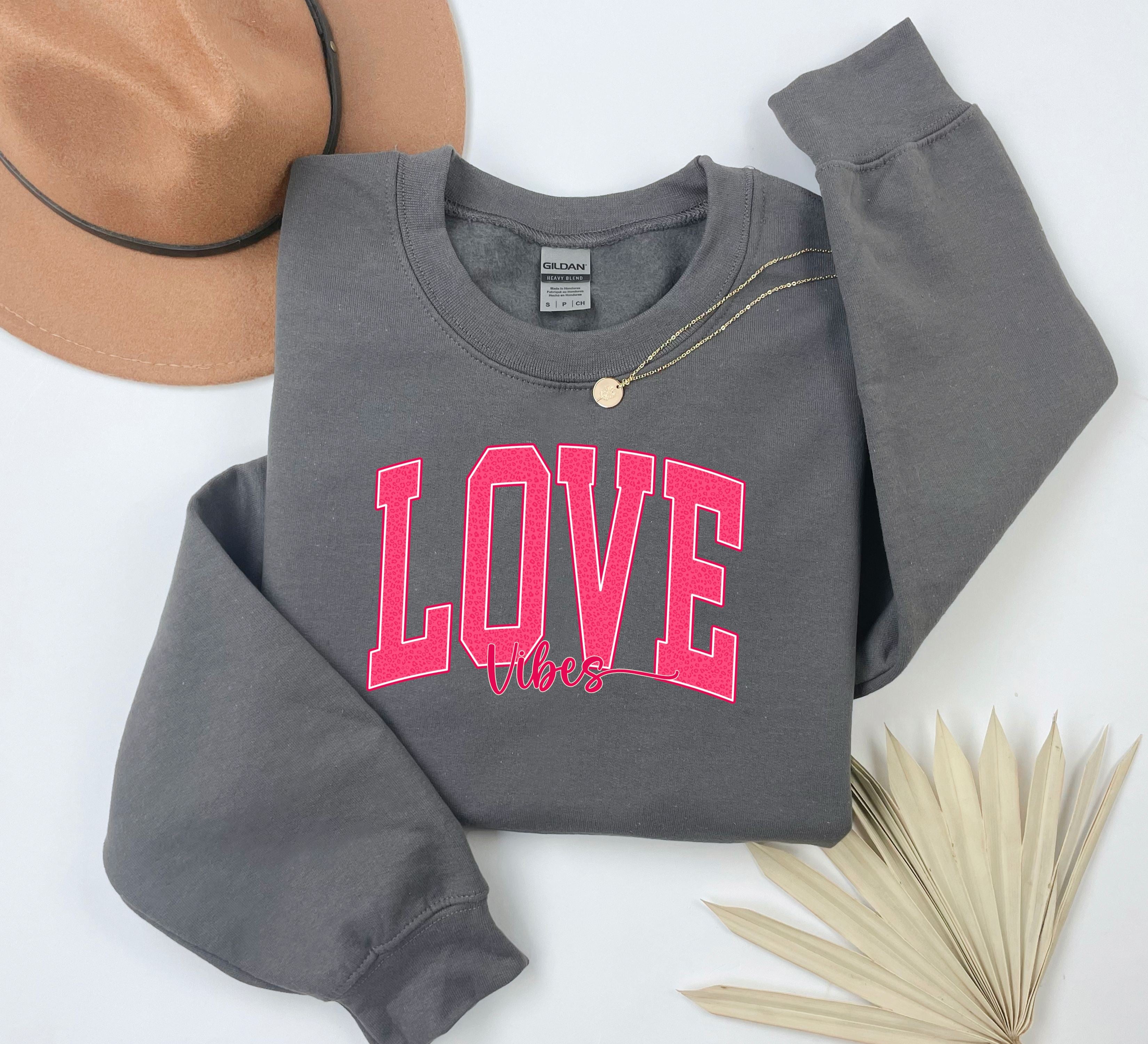 a gray sweatshirt with a pink love on it