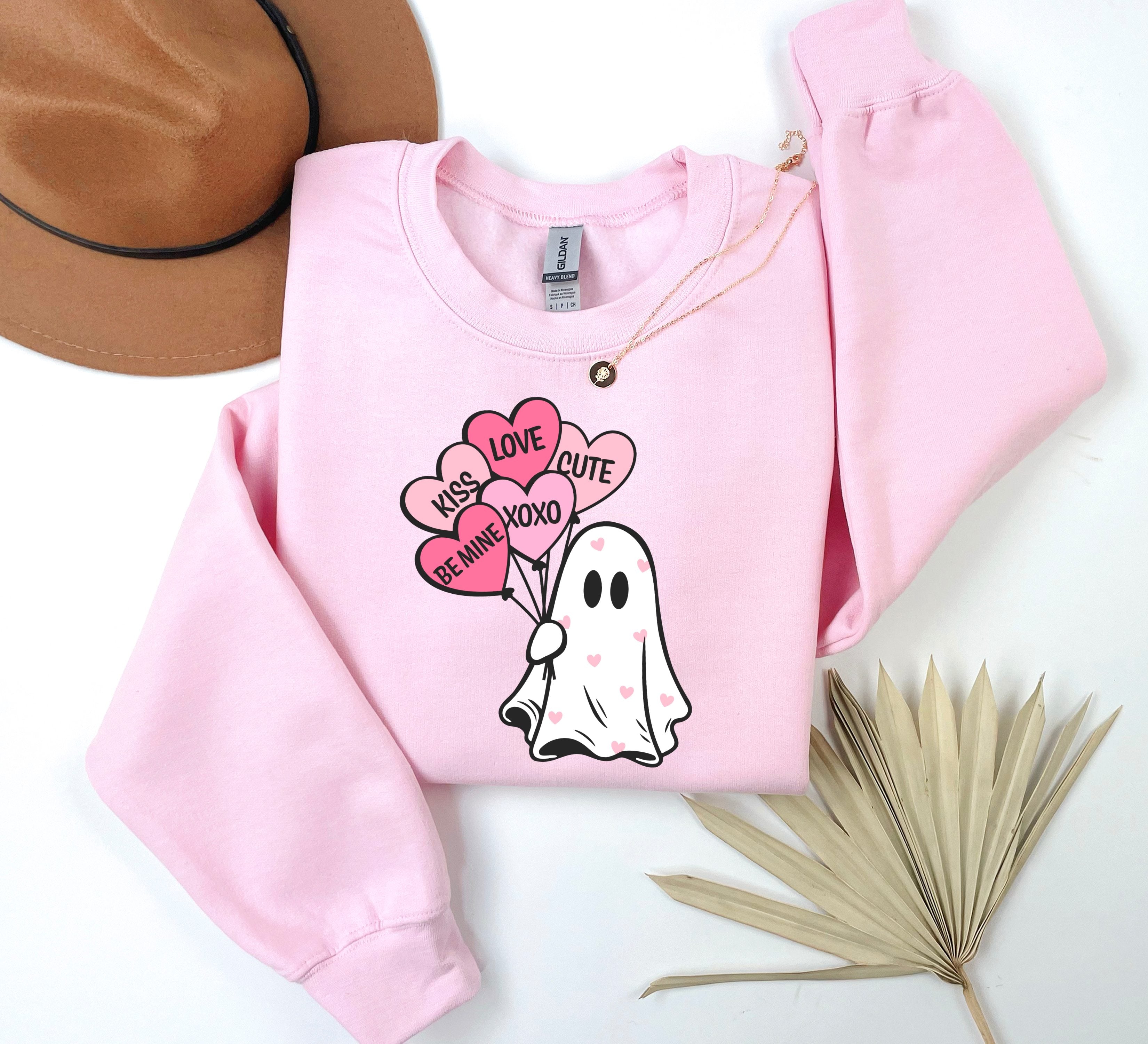 a pink sweater with a ghost holding a heart balloon