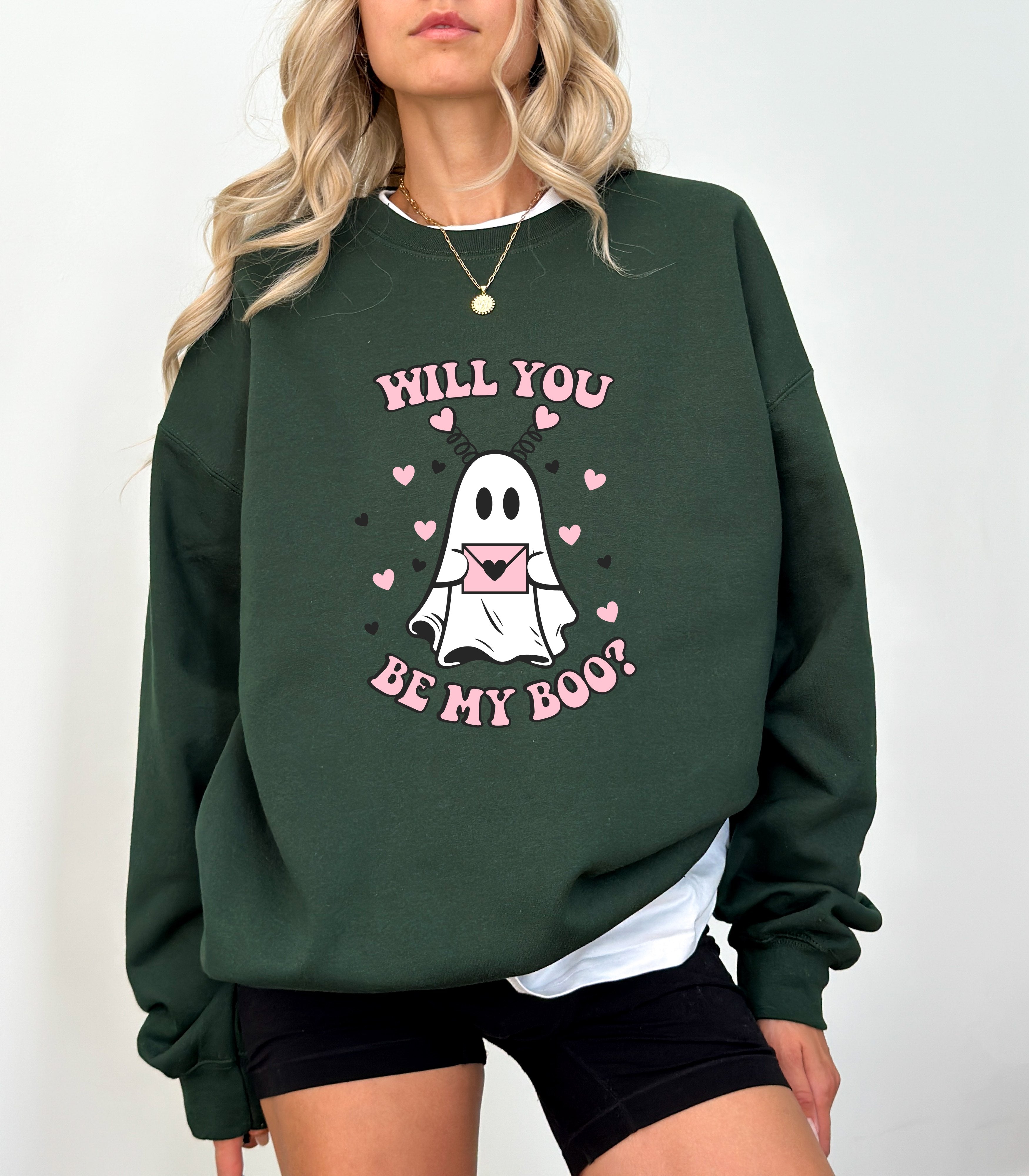 a woman wearing a green sweatshirt that says will you be my boo?