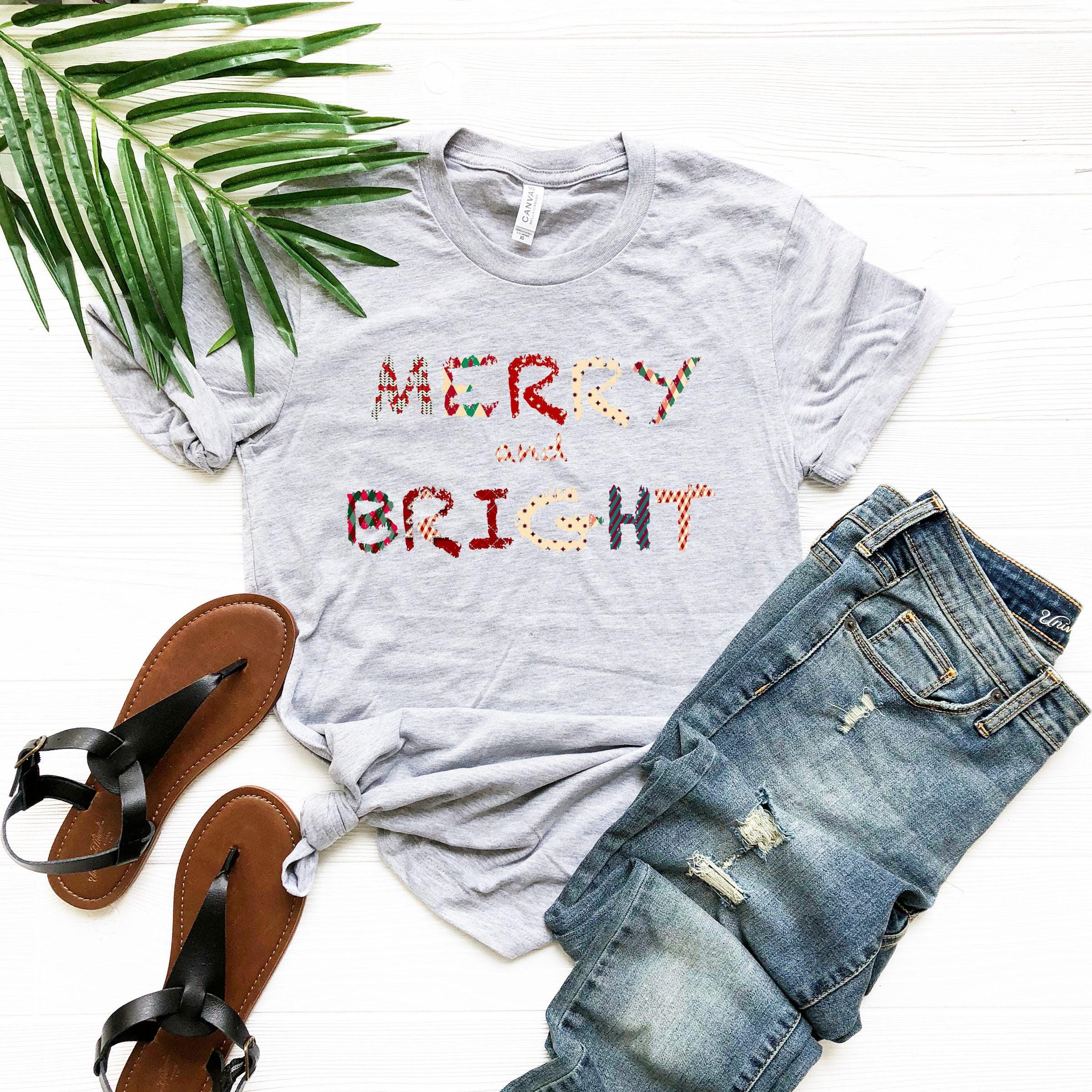 a t - shirt that says merry and bright next to a pair of jeans and