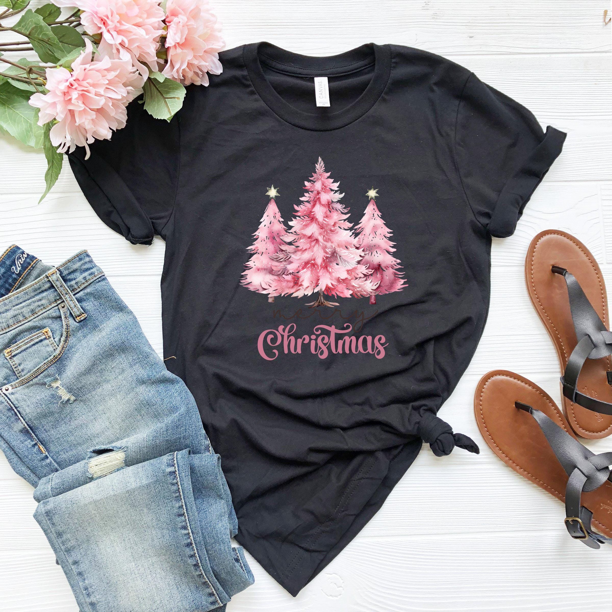 a t - shirt with christmas trees on it next to a pair of jeans