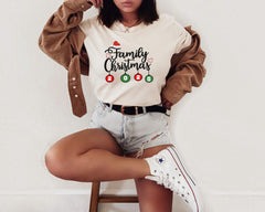 a woman sitting on a stool wearing a family christmas sweatshirt